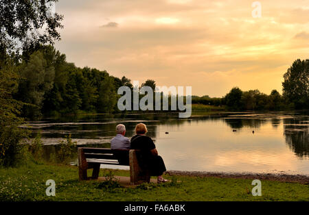 Couple assis sur un banc avec vue sur le lac avec lueur chaude de soir, St Chad's Water off Wilne Rd, Derby Banque D'Images