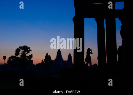 Silhouette d'une femme prenant photo du lever du soleil Banque D'Images