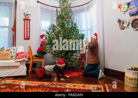 Père et trois enfants décorer un arbre de Noël Banque D'Images