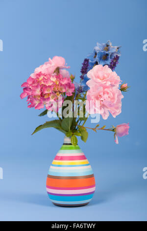 Bouquet de fleurs mixtes en vase colorés sur fond coloré Banque D'Images