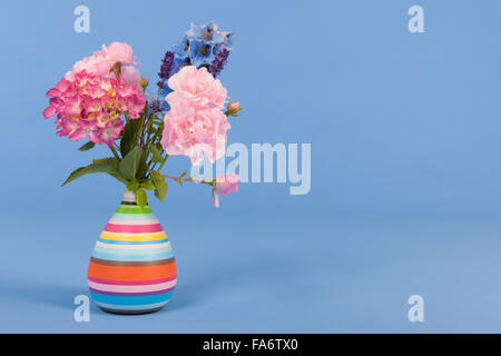 Bouquet de fleurs mixtes en vase colorés sur fond coloré Banque D'Images