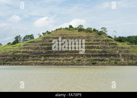 Mur en terrasses du canal de Panama Panama | CANAL DE PANAMA, Panama — Des terrasses en gradins creusées dans une colline le long du canal de Panama stabilisent les pentes excavées de la Coupe Gaillard, l'excavation de 8,5 miles (13,7 km) à travers la ligne de partage des eaux continentale qui s'est avérée être la partie géologiquement la plus dangereuse de toute la voie navigable. Les glissements de terrain ont entravé la construction et ont nécessité des ré-excavations et des terrassements répétés depuis l'ouverture du canal le 15 août 1914. Banque D'Images