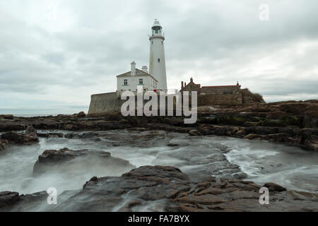 St Marys phare au crépuscule avec des vagues se brisant sur les rochers. Banque D'Images