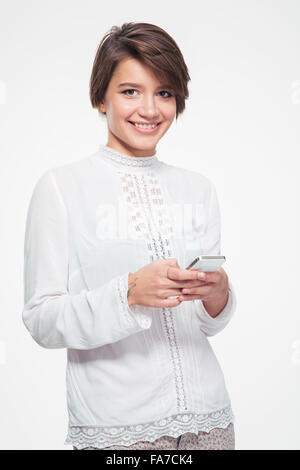 Smiling attractive young woman avec les cheveux courts et permanent à l'aide de téléphone sur fond blanc Banque D'Images