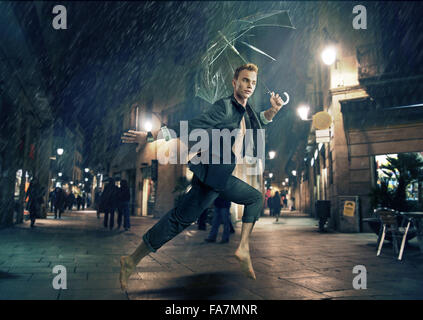 Cheerful young businessman fonctionnant en temps de pluie Banque D'Images