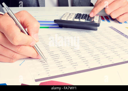 Libre d'un young caucasian businessman checking des comptes avec une calculatrice dans son bureau Banque D'Images