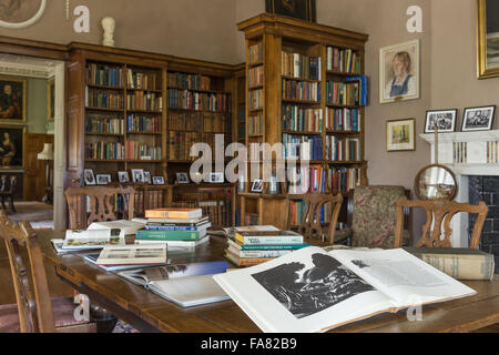 Les livres qui peuvent être consultés par les visiteurs sont disposés sur une table dans la bibliothèque de Killerton, Devon. Cette chambre a été transformée en bibliothèque au cours de l'époque édouardienne, et la salle à manger peut être vu à travers les portes ouvertes. Banque D'Images