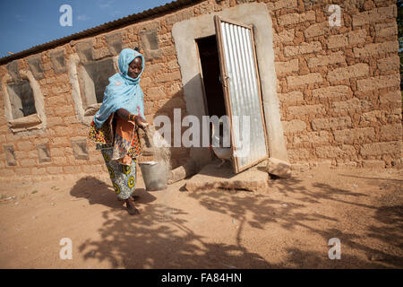 Un agriculteur nourrit ses poules en dehors de sa grange en Tengréla, village du Burkina Faso. Banque D'Images