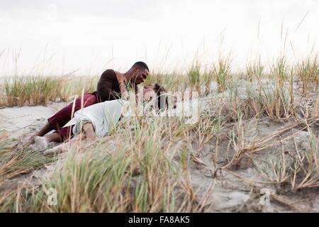 Couple lying in sand dunes, face à face Banque D'Images