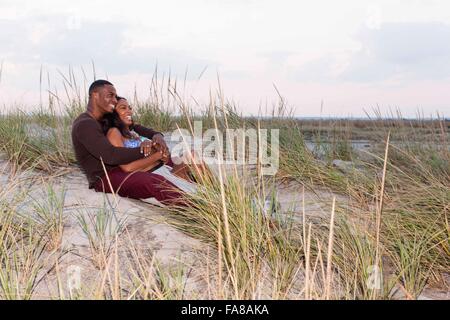 Couple lying in sand dunes, hugging Banque D'Images