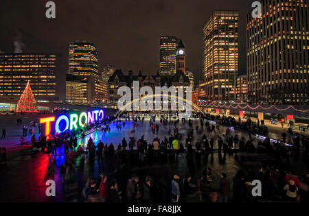 Toronto, Canada. 22 Décembre, 2015. Grand groupe de personnes de célébrer des fêtes de Noël et de patinage sur glace de Nathan Phillips Square avec signe de couleur multi-illuminé de Toronto, Arbre de Noël, Toronto l'ancien Hôtel de Ville, bâtiment en arrière-plan Crédit : CharlineXia/Alamy Live News Banque D'Images