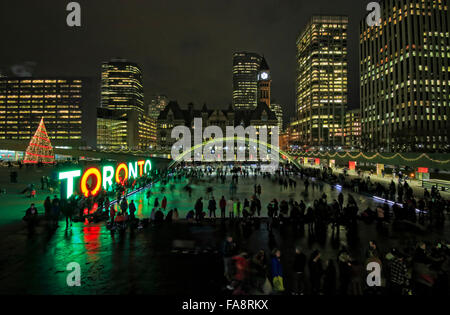 Toronto, Canada. 22 Décembre, 2015. Les gens célébrant des fêtes de Noël et de patinage sur glace de Nathan Phillips Square avec signe de couleur multi-illuminé de Toronto, l'arbre de Noël municipal de Toronto, l'ancien Hôtel de Ville, bâtiment en arrière-plan Crédit : CharlineXia/Alamy Live News Banque D'Images