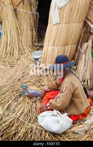 Femme âgée assise devant une cabane sur les îles flottantes Uros, Los, Lac Titicaca, région de Puno, Pérou, Amérique du Sud Banque D'Images