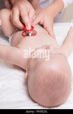 Pédiatre en sarrau blanc examine trois mois bébé garçon à l'aide d'un stéthoscope Banque D'Images