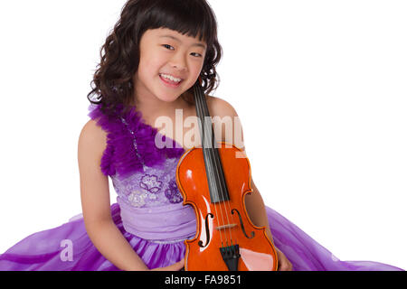 Un portrait d'un mignon, heureux et jeune japonaise dans une robe pourpre sur fond blanc avec un violon. Banque D'Images