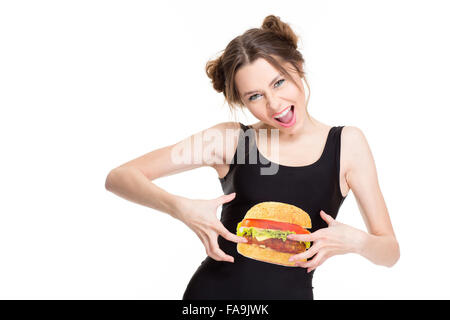 Jeune femme criant ludique en noir top avec hamburger imprimer blagues et de toucher son ventre isolé sur fond blanc Banque D'Images