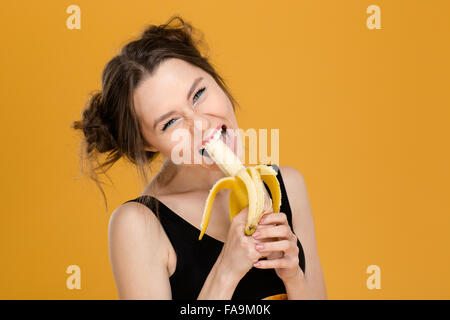 Portrait de belle jeune femme drôle sur fond jaune banane manger Banque D'Images