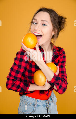 Belle jeune femme en chemise à carreaux sur fond jaune pamplemousse holding Banque D'Images