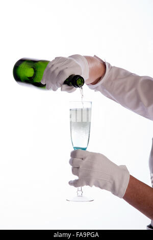 Serveuse portant des gants de coton blanc versant vin mousseux dans une bouteille verte Banque D'Images