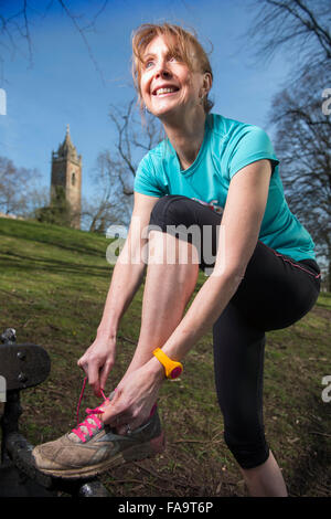 Une femme portant un jogger laçage activity tracker ses formateurs avant une course UK Banque D'Images