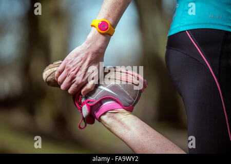 Une femme portant un jogger stretching activity tracker avant une course UK Banque D'Images