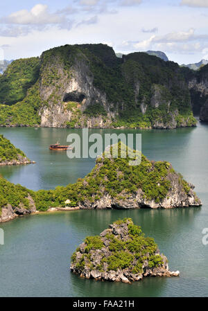 Bateau touristique en voyageant entre les petites îles rocheuses dans la célèbre baie d'Halong au Vietnam, Asie Banque D'Images