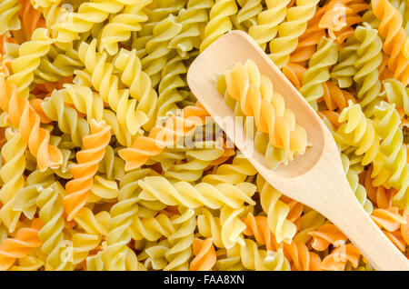 Les pâtes rotini trois couleurs avec une cuillère de bois. Banque D'Images