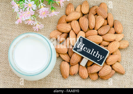 Les amandes et le lait d'amande dans du verre avec des tag sur sac arrière-plan. Banque D'Images