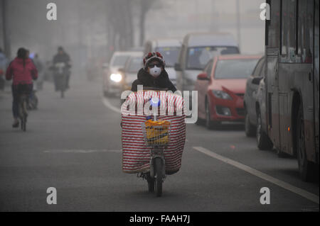 Les gens portent des masques qu'un épais brouillard de pollution de l'air des enveloppes Beijing, Chine. 25-Déc-2015 Banque D'Images