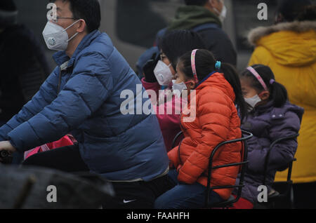 Les gens portent des masques qu'un épais brouillard de pollution de l'air des enveloppes Beijing, Chine. 25-Déc-2015 Banque D'Images