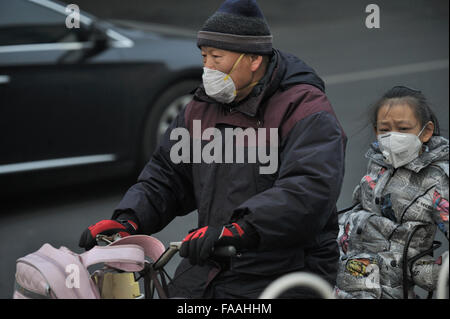 Les gens portent des masques qu'un épais brouillard de pollution de l'air des enveloppes Beijing, Chine. 25-Déc-2015 Banque D'Images