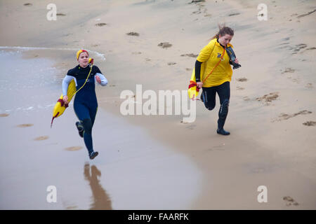 Bournemouth, Dorset, UK. Dec 25, 2015. Noël blanc au Dip, Boscombe Bournemouth, Dorset, UK le jour de Noël. Braves bénévoles plongent dans la mer froide malgré le temps humide breezy misty, pour la 8e annual charity matin de Noël nager, vêtus de costumes habillés de fantaisie et la collecte de fonds pour les soins à l'échelle locale, Macmillan un spécialiste de l'unité de soins palliatifs pour les patients dans la communauté locale. Des centaines ont pris part à l'événement qui est devenu une tradition populaire pour beaucoup d'autres avant leur déjeuner. Les sauveteurs RNLI le long de la mer - en fonction de l'événement. Credit : Carolyn Jenkins/Alamy Live News Banque D'Images