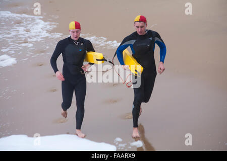 Bournemouth, Dorset, UK. Dec 25, 2015. Noël blanc au Dip, Boscombe Bournemouth, Dorset, UK le jour de Noël. Braves bénévoles plongent dans la mer froide malgré le temps humide breezy misty, pour la 8e annual charity matin de Noël nager, vêtus de costumes habillés de fantaisie et la collecte de fonds pour les soins à l'échelle locale, Macmillan un spécialiste de l'unité de soins palliatifs pour les patients dans la communauté locale. Des centaines ont pris part à l'événement qui est devenu une tradition populaire pour beaucoup d'autres avant leur déjeuner. Les sauveteurs RNLI le long de la mer - en fonction de l'événement. Credit : Carolyn Jenkins/Alamy Live N Banque D'Images