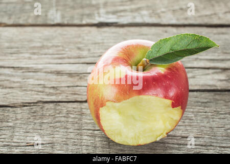 Mordu dans une pomme rouge sur une planche en bois rustique Banque D'Images