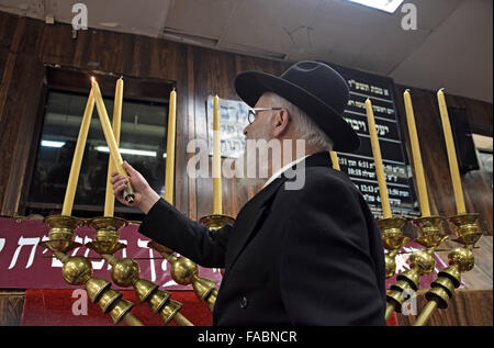 Un rabbin juif orthodoxe l'éclairage des bougies sur un géant Chanukkah menorah. À Brooklyn, New York Banque D'Images