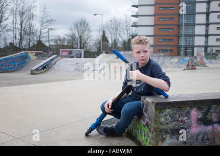 Jeune, blond garçon de 12 ans, seul à la pensive dans un environnement urbain skate park Banque D'Images