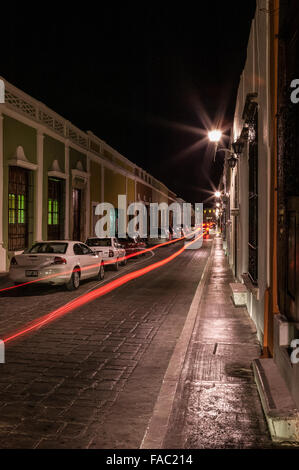 Photo nocturne des feux arrière de voiture créant un long sentier rouge de feu arrière en bas d'une rue dans la ville historique Yucatan de Campeche, Mexique. Banque D'Images