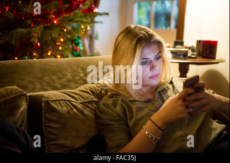 Une fille consulte ses mobile smartphone à Noël Banque D'Images