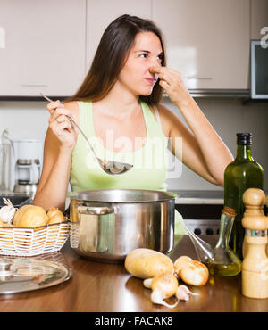 Jeune femme prend couvercle de casserole et sentir le renfermé à la maison cuisine Banque D'Images