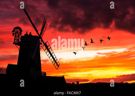 Un moulin à vent à la mer, suivant le CLAJ North Norfolk, Royaume-Uni, avec l'église de Blakeney en arrière-plan au coucher du soleil. Banque D'Images