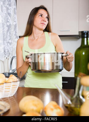 Jeune fille prend couvercle de casserole et sentir le renfermé à cuisine Banque D'Images