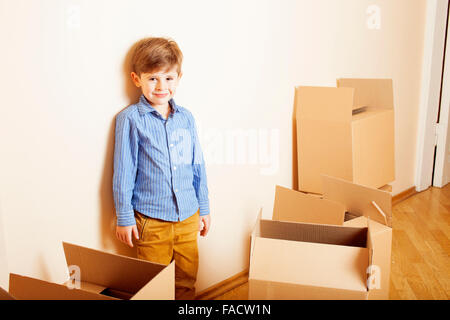 Peu cute boy dans la salle vide, remoove de nouvelle maison. La maison seule boîtes emong Banque D'Images