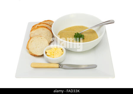 Brocolli et Stilton soupe dans un bol avec du pain croustillant et du beurre sur une assiette blanche contre isolés Banque D'Images