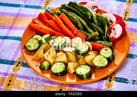 Louche de jeunes légumes fraîchement récoltés à la vapeur y compris les carottes, en Coupe ondulée, de pois et de pommes de terre des matraques Banque D'Images