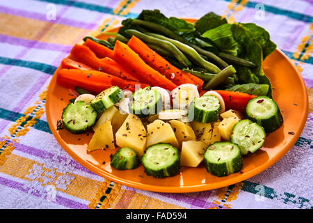 Louche de jeunes légumes fraîchement récoltés à la vapeur y compris les carottes, en Coupe ondulée, de pois et de pommes de terre des matraques Banque D'Images