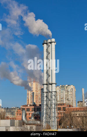 Des tuyaux d'une centrale thermique avec une cigarette contre un paysage de ville Banque D'Images