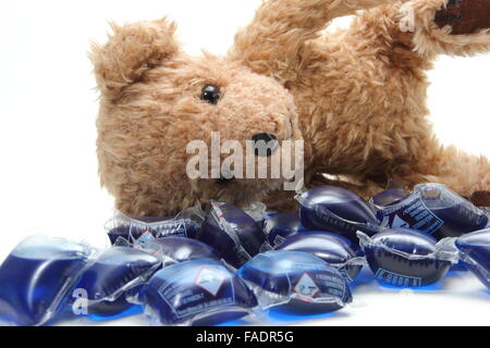 Lessive liquide gélules entourent un ours en peluche de l'enfant - UK Banque D'Images