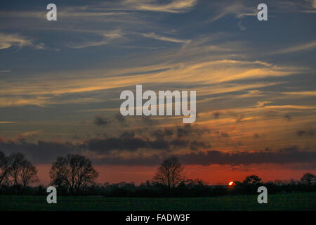 Nuages au coucher du soleil, près d'une silhouette. La lumière du soleil traversant les nuages au coucher du soleil. Les rayons de soleil fanning out les nuages minces. Banque D'Images