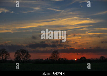 Nuages au coucher du soleil, près d'une silhouette. La lumière du soleil traversant les nuages au coucher du soleil. Les rayons de soleil fanning out les nuages minces. Banque D'Images