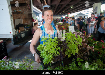 Femme vendant des plantes à un marché de producteurs locaux Banque D'Images